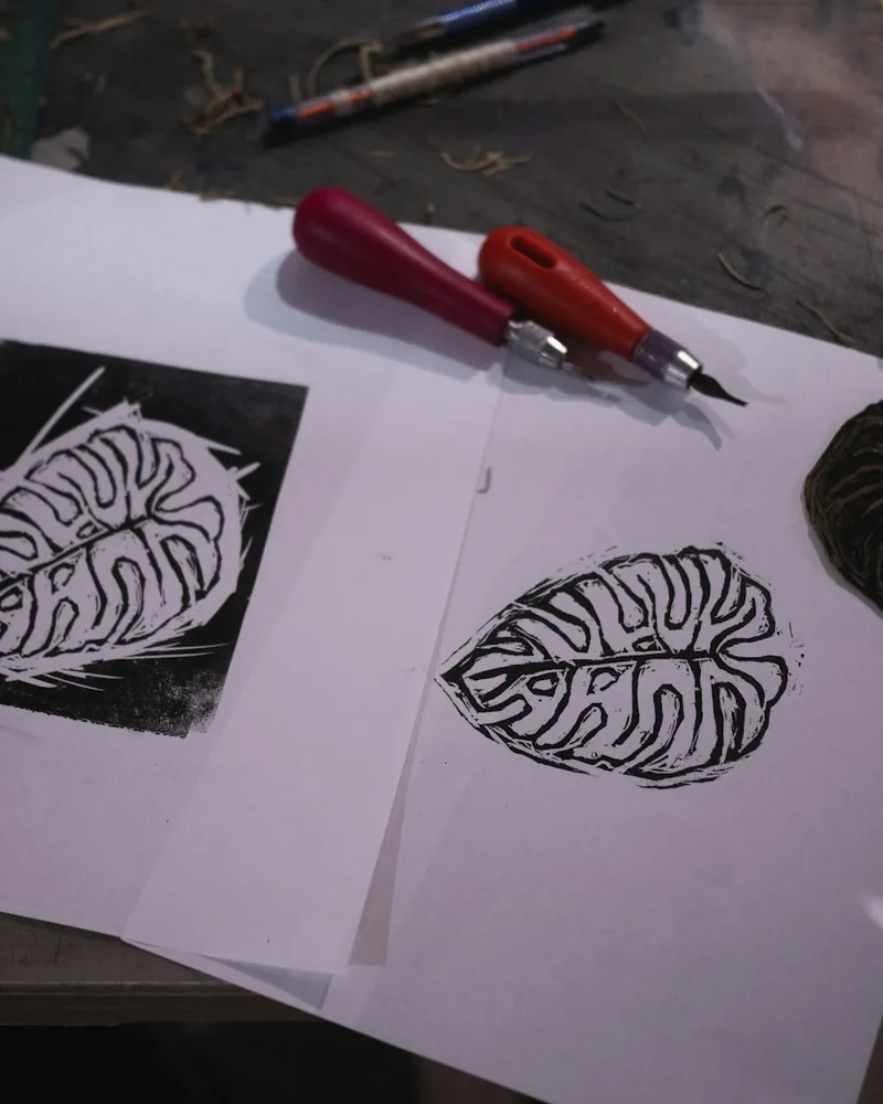 Estampa de una hoja obtenida por linograbado junto a una gubia de corte sobre papel
